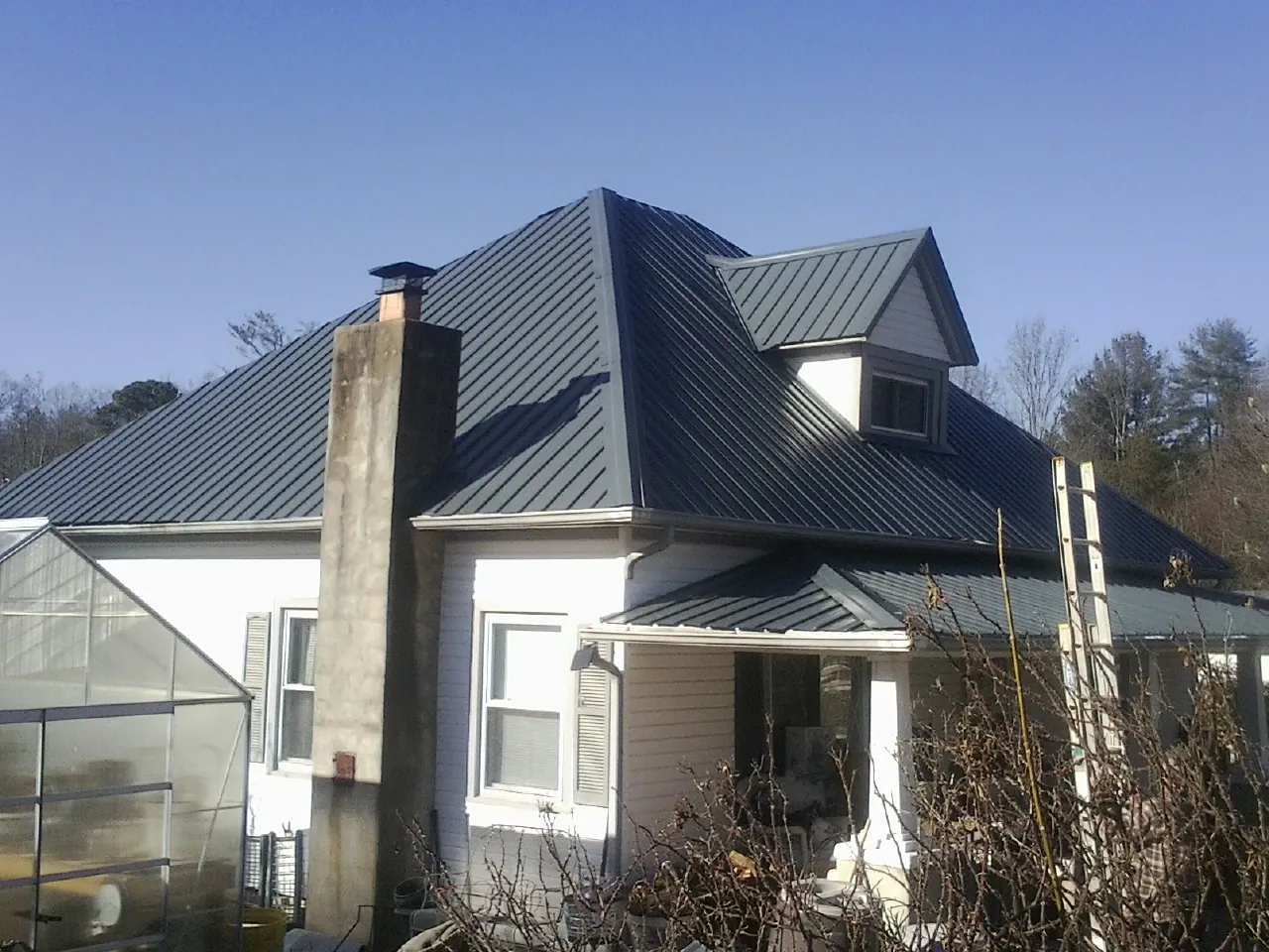 Dark blue standing seam metal roof on a white farmhouse with dormer — Slate & Tile Roof Repair by Roofing Brothers in Haydenville