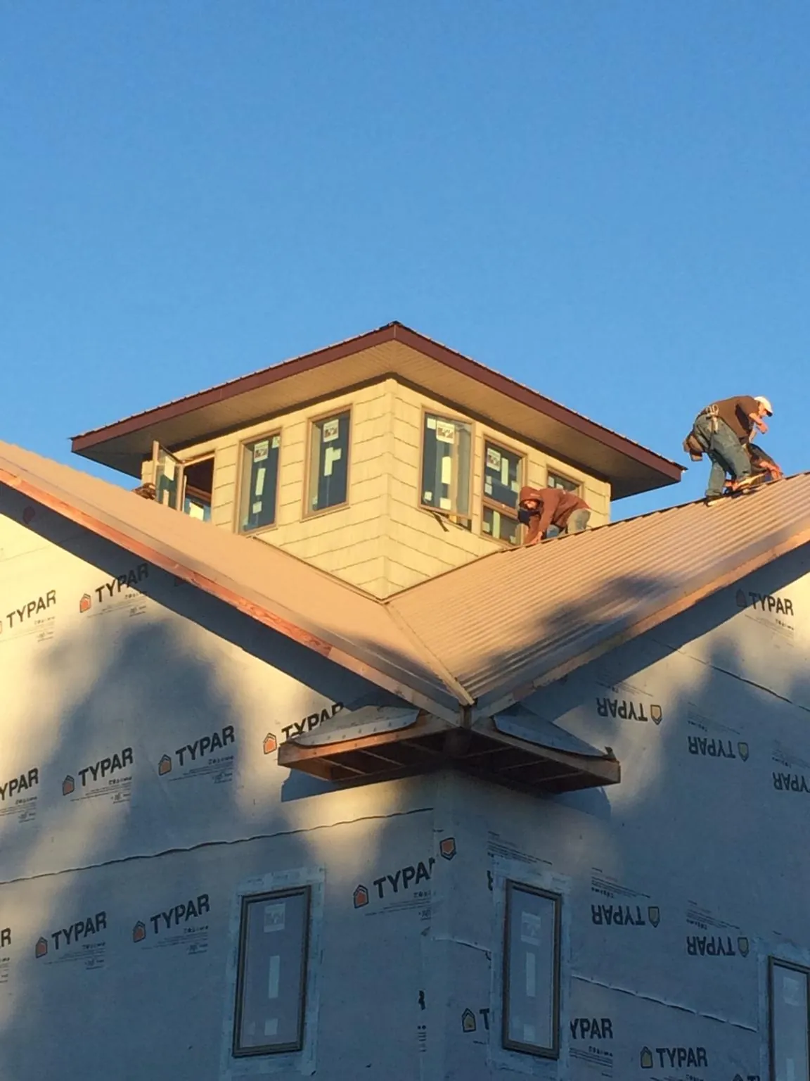 Roofers working around a rooftop cupola on a new metal roof at sunset — Roof Waterproofing in Haydenville by Roofing Brothers